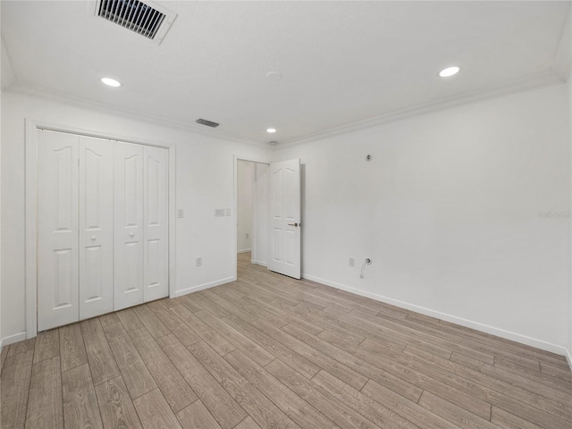 unfurnished bedroom with ornamental molding, a closet, and light wood-type flooring