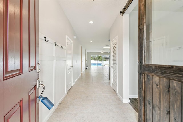 hallway with a barn door and light tile patterned flooring