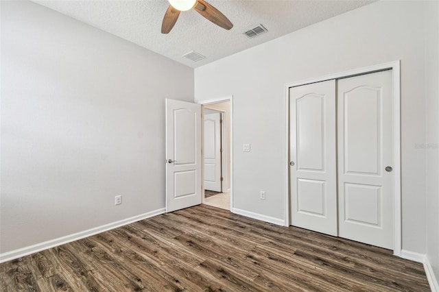 unfurnished bedroom featuring ceiling fan, a textured ceiling, dark hardwood / wood-style flooring, and a closet