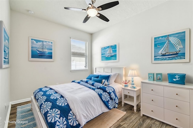 bedroom with dark wood-type flooring, ceiling fan, and a textured ceiling