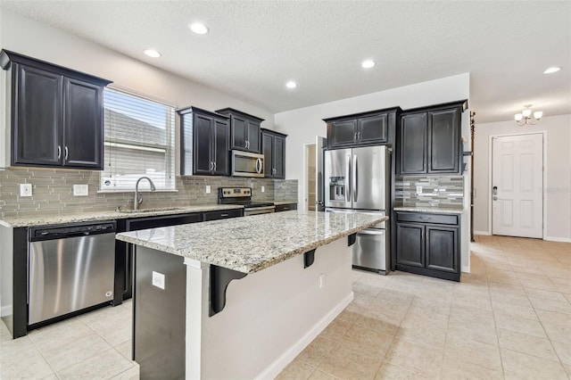 kitchen with sink, a kitchen island, light stone countertops, and appliances with stainless steel finishes