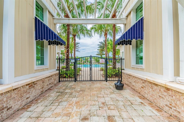 view of gate with a swimming pool and a patio area