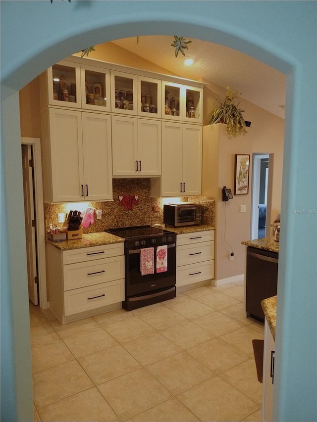 kitchen featuring light stone counters, vaulted ceiling, black electric range, white cabinets, and backsplash