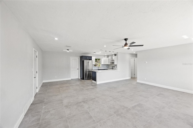 unfurnished living room with a textured ceiling and ceiling fan