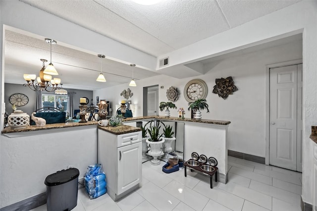 kitchen featuring white cabinetry, hanging light fixtures, a notable chandelier, kitchen peninsula, and a textured ceiling