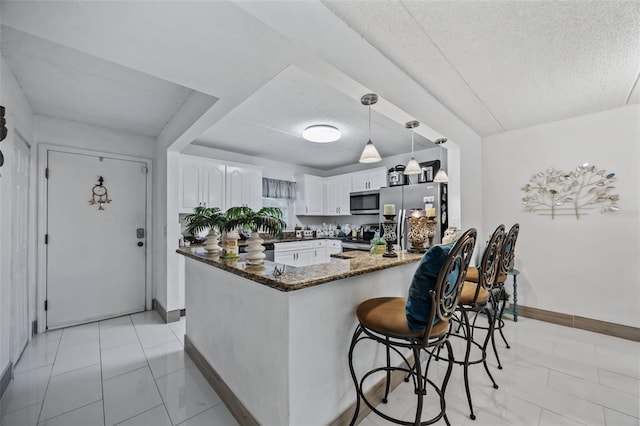 kitchen featuring white cabinetry, dark stone countertops, kitchen peninsula, stainless steel appliances, and a textured ceiling