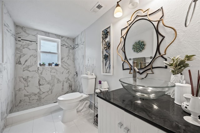 bathroom featuring vanity, toilet, and a tile shower