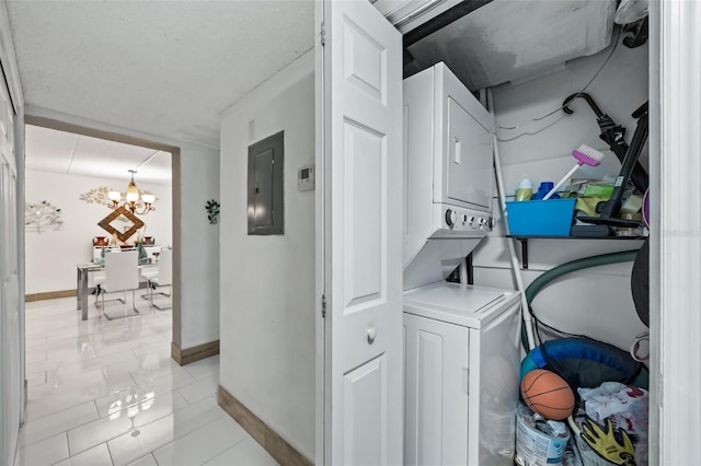 clothes washing area with a notable chandelier, stacked washer / drying machine, and electric panel