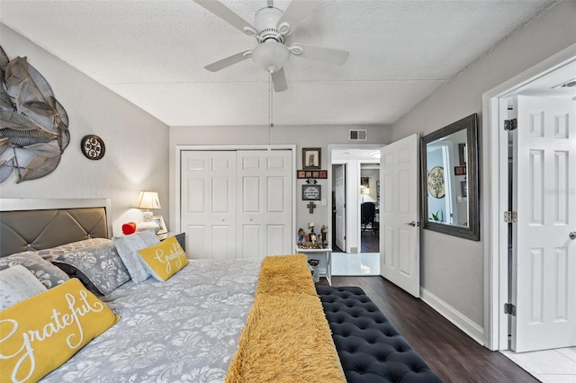 bedroom with ceiling fan, dark hardwood / wood-style floors, a textured ceiling, and a closet