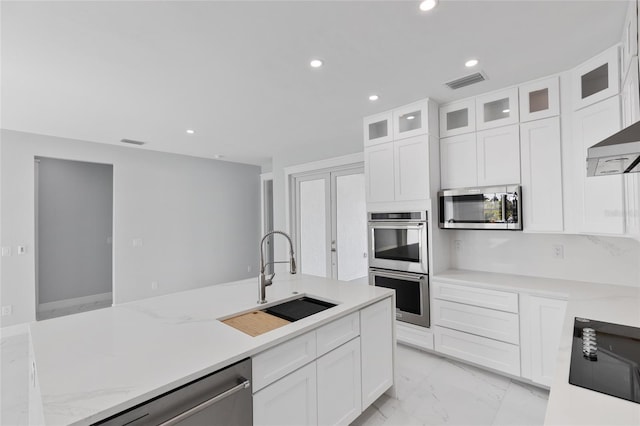 kitchen featuring sink, white cabinets, stainless steel appliances, light stone countertops, and wall chimney exhaust hood