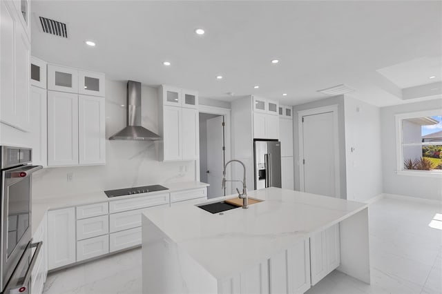 kitchen with black electric cooktop, high quality fridge, wall chimney exhaust hood, and a kitchen island with sink