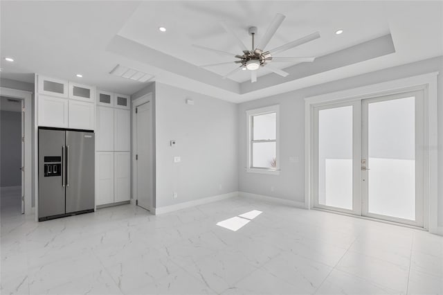 unfurnished living room with french doors, ceiling fan, and a tray ceiling