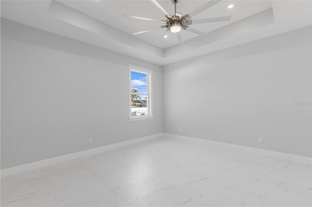 spare room with a raised ceiling and ceiling fan