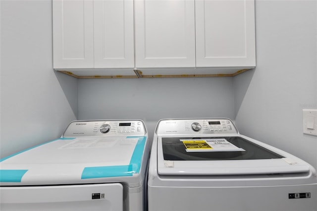 clothes washing area featuring separate washer and dryer and cabinets