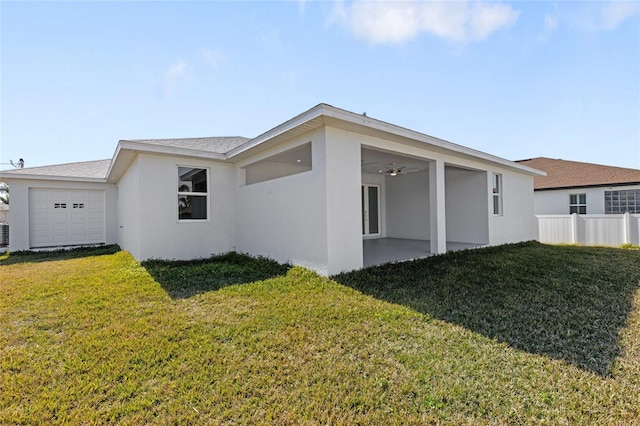 rear view of house with a garage, a yard, and ceiling fan