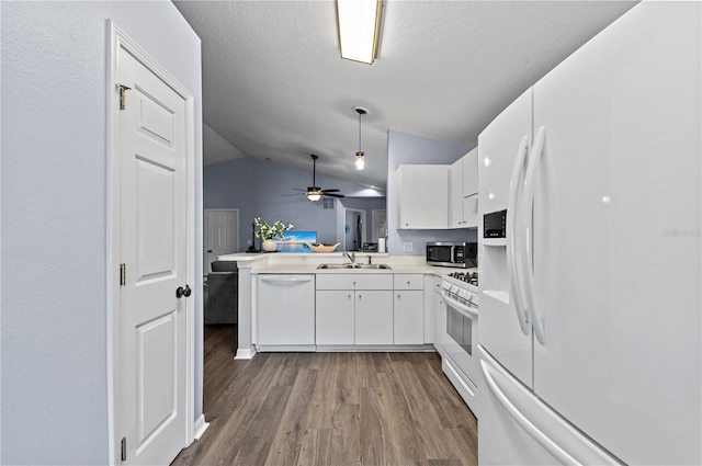 kitchen featuring sink, white cabinetry, vaulted ceiling, kitchen peninsula, and white appliances