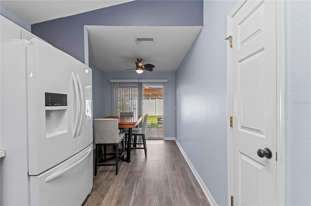 kitchen with hardwood / wood-style floors, white refrigerator with ice dispenser, white cabinets, and ceiling fan