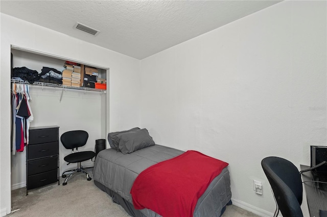 carpeted bedroom with a closet and a textured ceiling