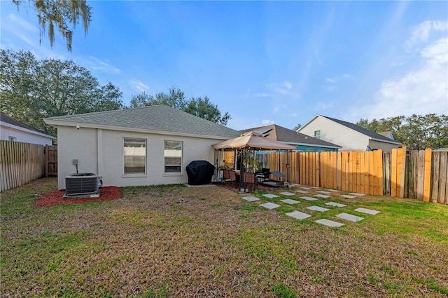 back of property with a gazebo, central AC, and a lawn