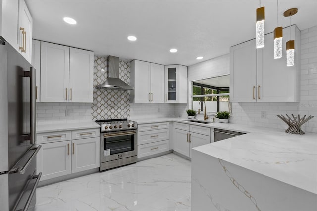 kitchen featuring pendant lighting, white cabinets, appliances with stainless steel finishes, and wall chimney range hood