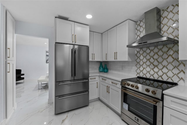 kitchen featuring tasteful backsplash, appliances with stainless steel finishes, wall chimney range hood, and white cabinets