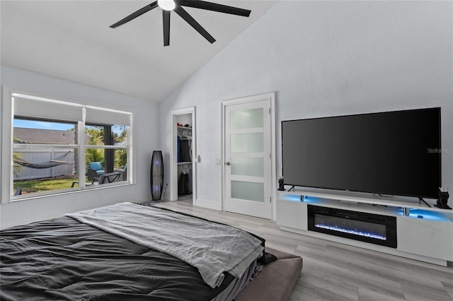 bedroom featuring lofted ceiling, a walk in closet, a closet, ceiling fan, and light hardwood / wood-style floors