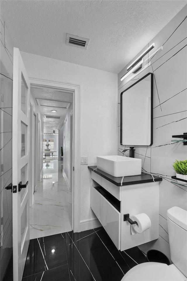 bathroom with vanity, a textured ceiling, and toilet