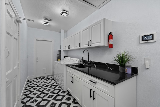 kitchen featuring a textured ceiling, sink, washer and dryer, and white cabinets