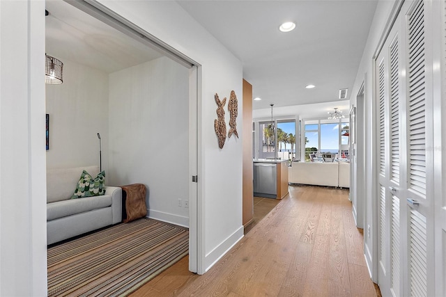 corridor with an inviting chandelier and light hardwood / wood-style floors