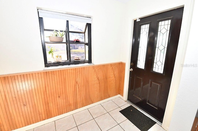 entrance foyer featuring wooden walls and light tile patterned floors