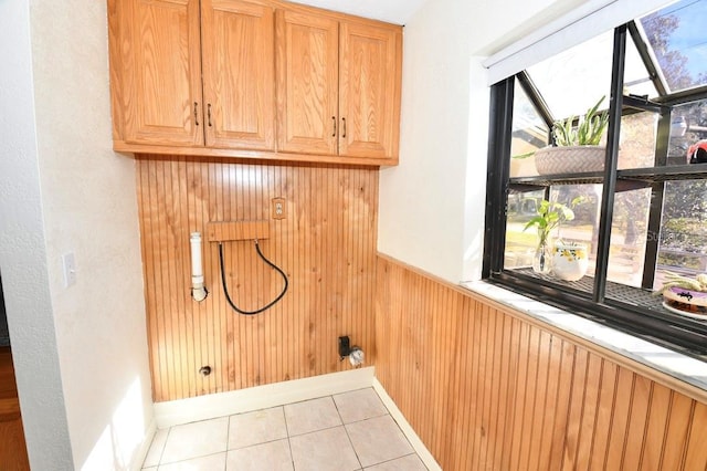 washroom featuring cabinets, electric dryer hookup, light tile patterned floors, and wood walls