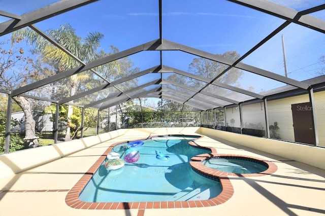 view of pool featuring an in ground hot tub, glass enclosure, and a patio area