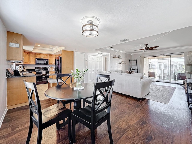 dining room featuring dark hardwood / wood-style flooring, sink, ornamental molding, and a raised ceiling