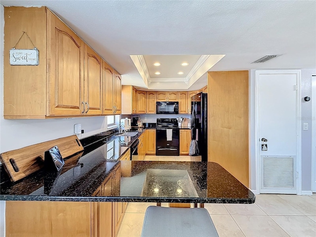 kitchen featuring sink, dark stone countertops, a raised ceiling, kitchen peninsula, and black appliances