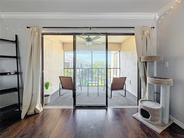 doorway to outside featuring ornamental molding, wood finished floors, a ceiling fan, and baseboards