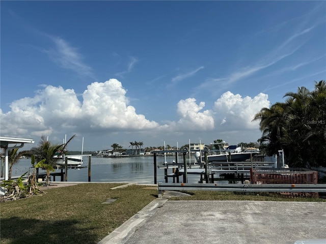 dock area featuring a water view, boat lift, and a yard