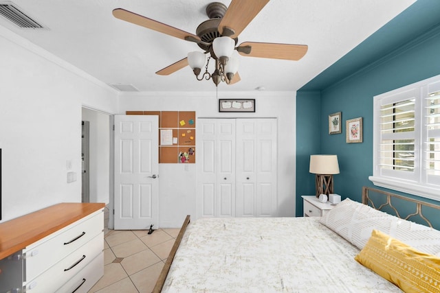 bedroom featuring a closet, ornamental molding, light tile patterned flooring, visible vents, and ceiling fan