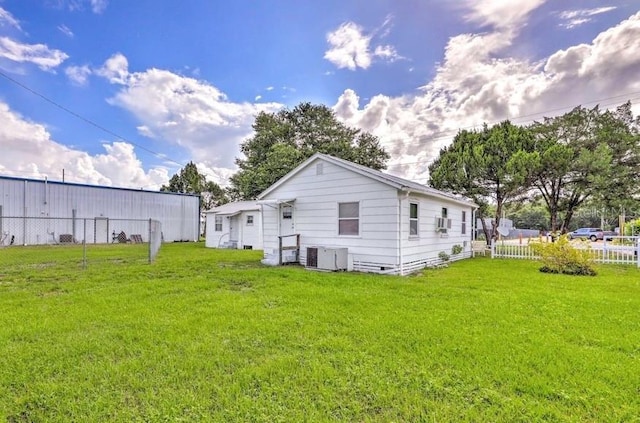 rear view of property with central AC and a yard