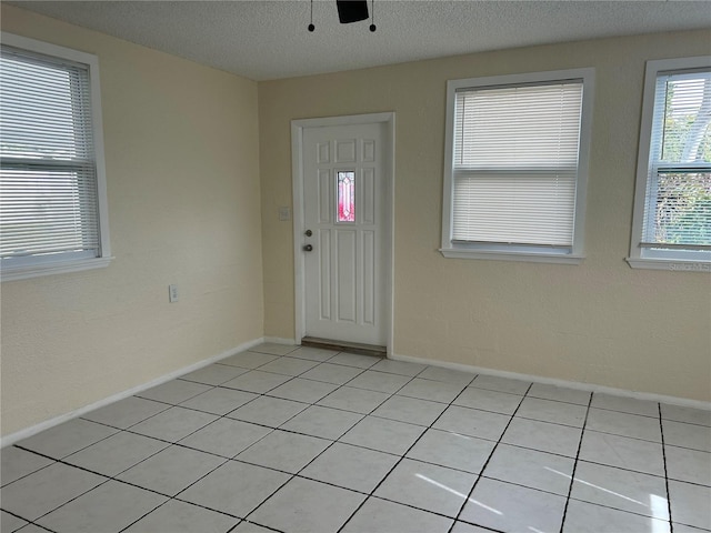 foyer entrance with ceiling fan and a textured ceiling