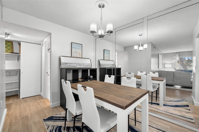 dining room featuring a chandelier, light hardwood / wood-style flooring, and a textured ceiling