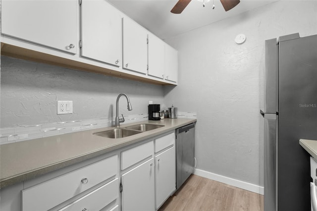 kitchen featuring appliances with stainless steel finishes, sink, white cabinets, ceiling fan, and light hardwood / wood-style floors