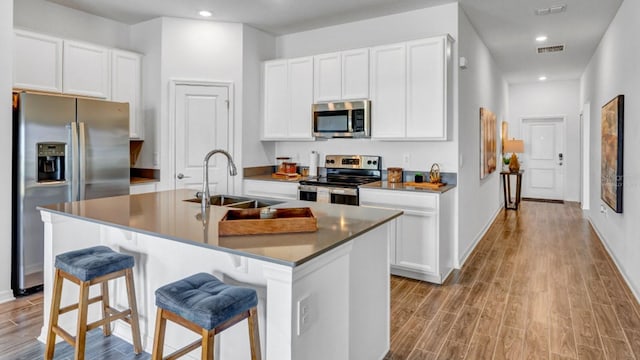 kitchen featuring an island with sink, appliances with stainless steel finishes, sink, and a kitchen bar