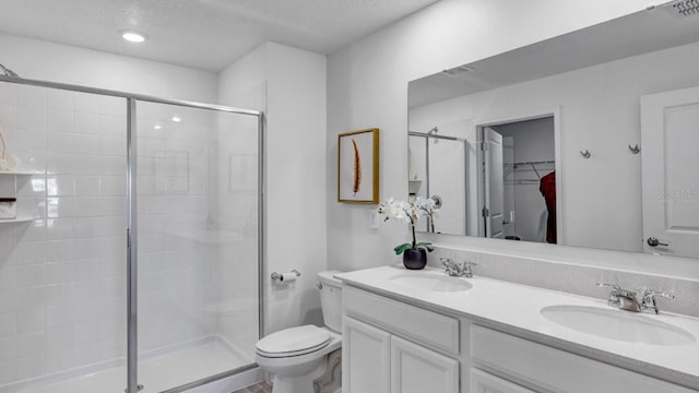 bathroom featuring vanity, toilet, a textured ceiling, and a shower with shower door