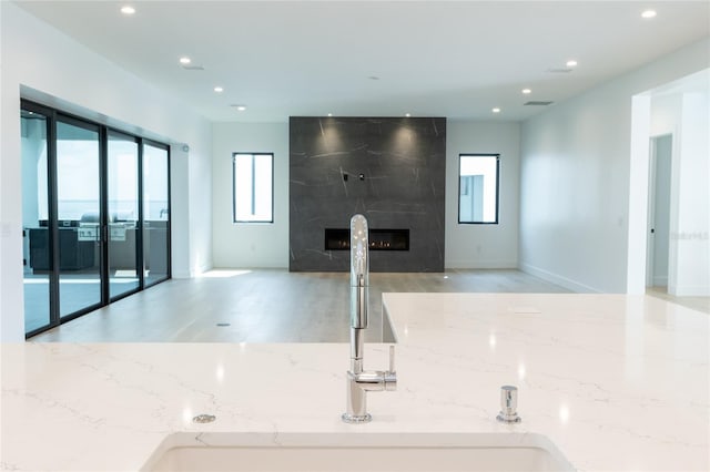 kitchen with sink, light stone countertops, a premium fireplace, and light wood-type flooring