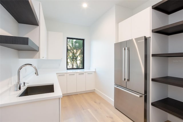 kitchen with sink, stainless steel fridge, light hardwood / wood-style floors, and white cabinets