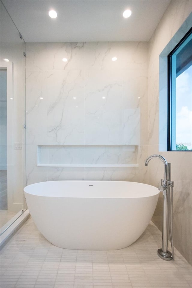 bathroom featuring a bath and tile walls