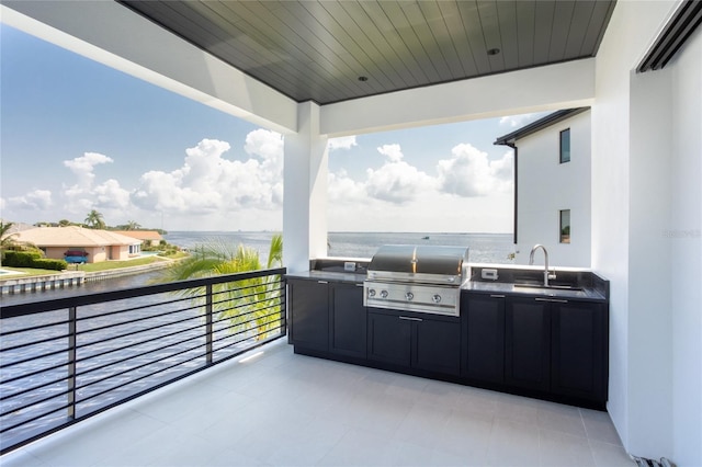 view of patio / terrace with sink, a water view, area for grilling, a balcony, and exterior kitchen