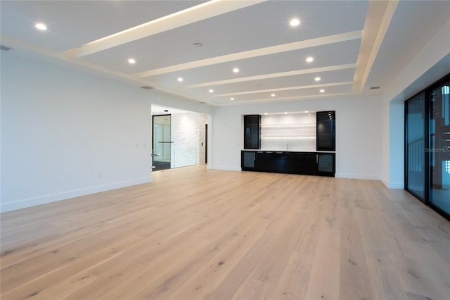 unfurnished living room with beamed ceiling, a tray ceiling, and light hardwood / wood-style flooring