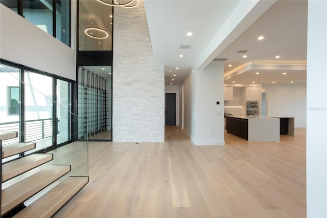 unfurnished living room with light hardwood / wood-style floors and a high ceiling