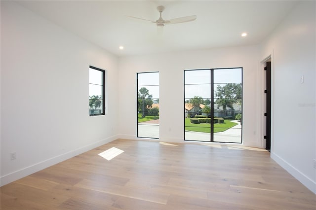 empty room featuring a wealth of natural light, light hardwood / wood-style flooring, and ceiling fan